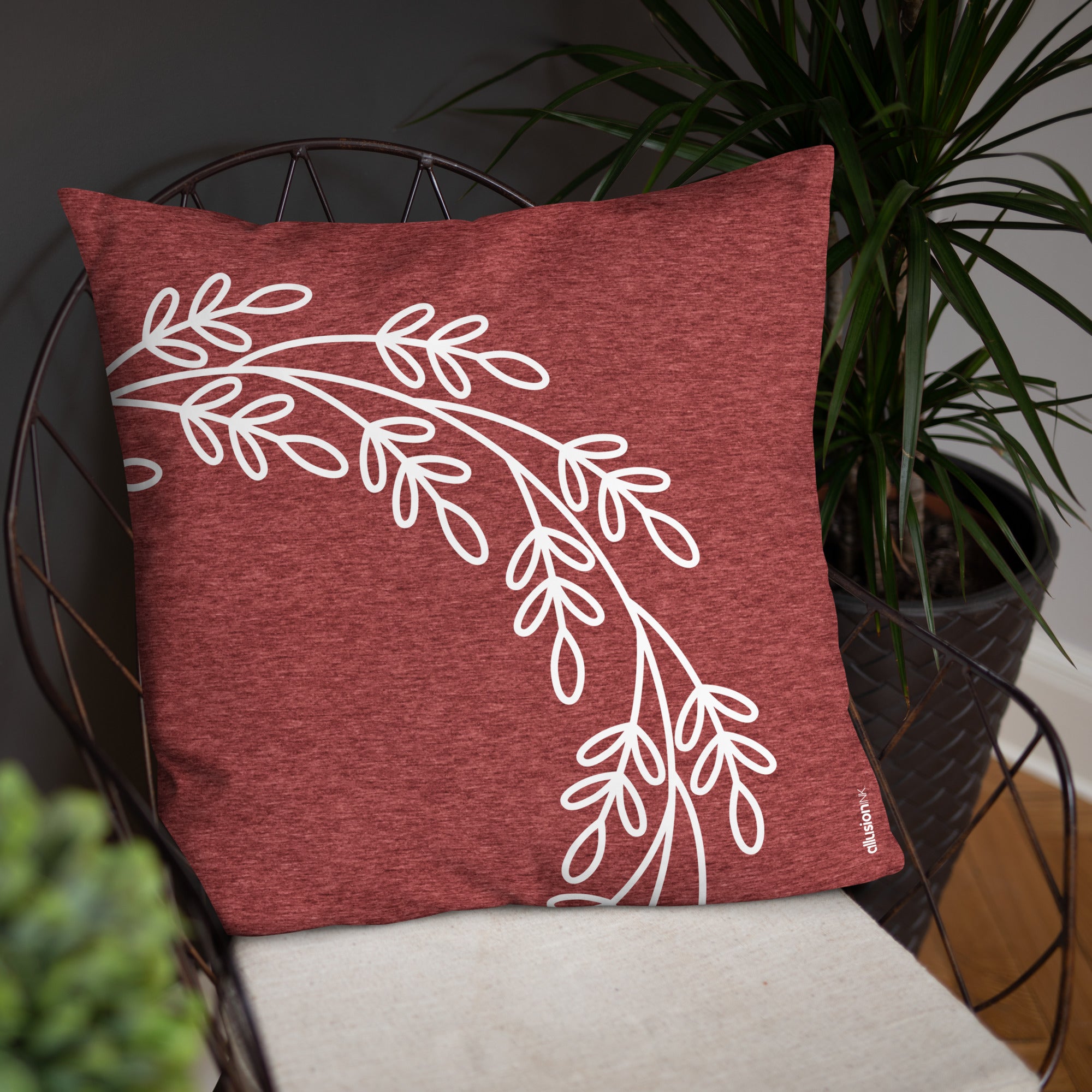 Burgundy red pillow with a white leaf motif on a minimalist chair, perfect for creating a warm and inviting corner in your home.