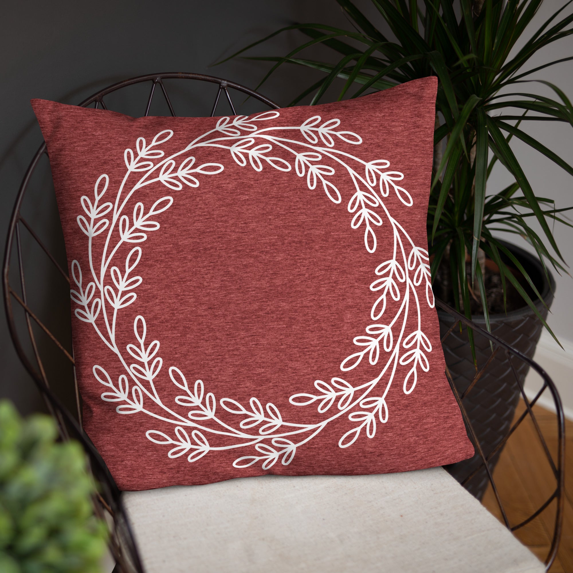 Burgundy red pillow with a white leaf wreath design placed on a chair, bringing timeless charm to any indoor space.