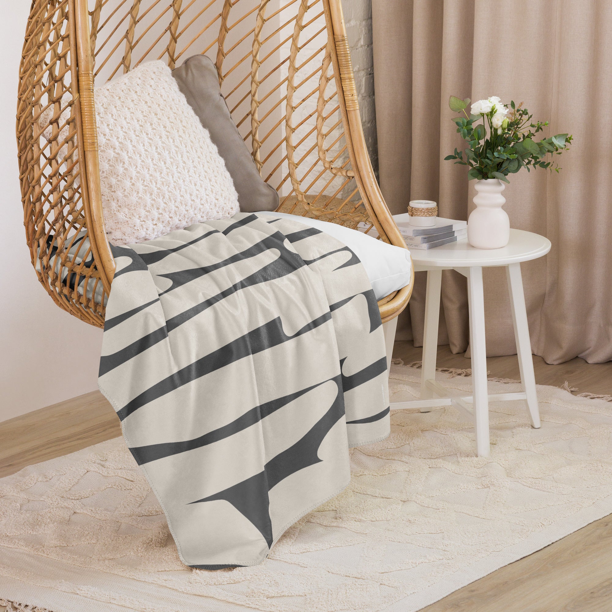 A cozy chair adorned with a sherpa blanket in an ivory and charcoal abstract design, styled alongside chic home decor.