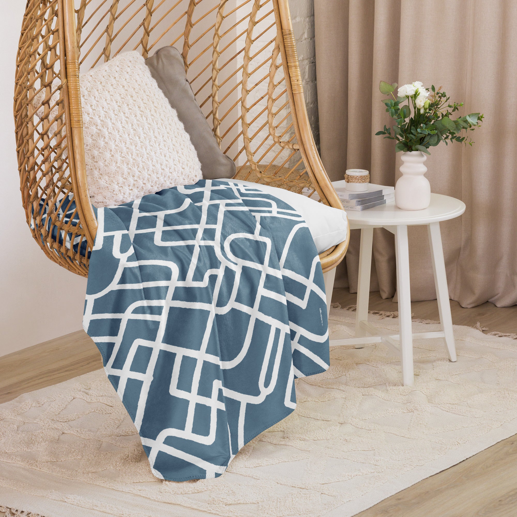 A cozy chair adorned with a sherpa blanket in blue and white geometric design, styled alongside home decor.