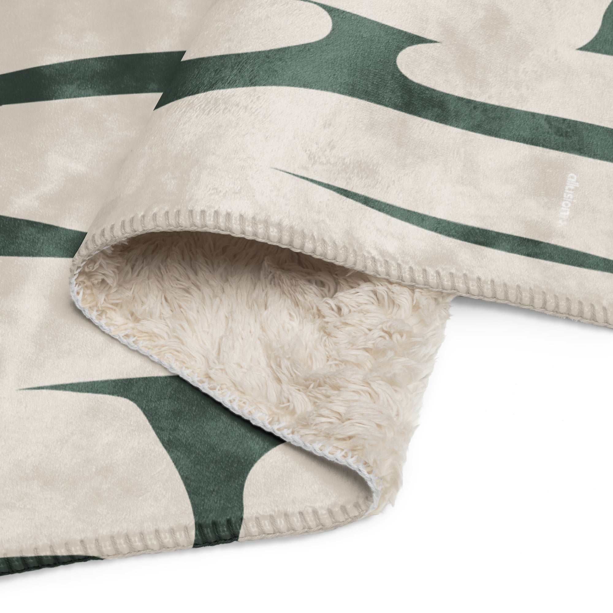 Close-up of green and beige sherpa blanket with detailed botanical pattern and soft fleece underside.