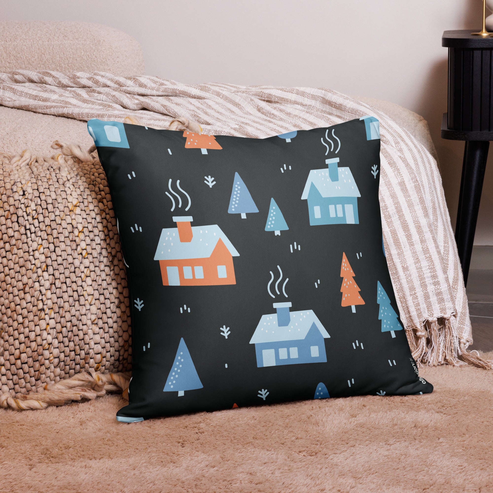 Large holiday throw pillow with colorful cabin and tree illustrations, displayed in a warm living space.