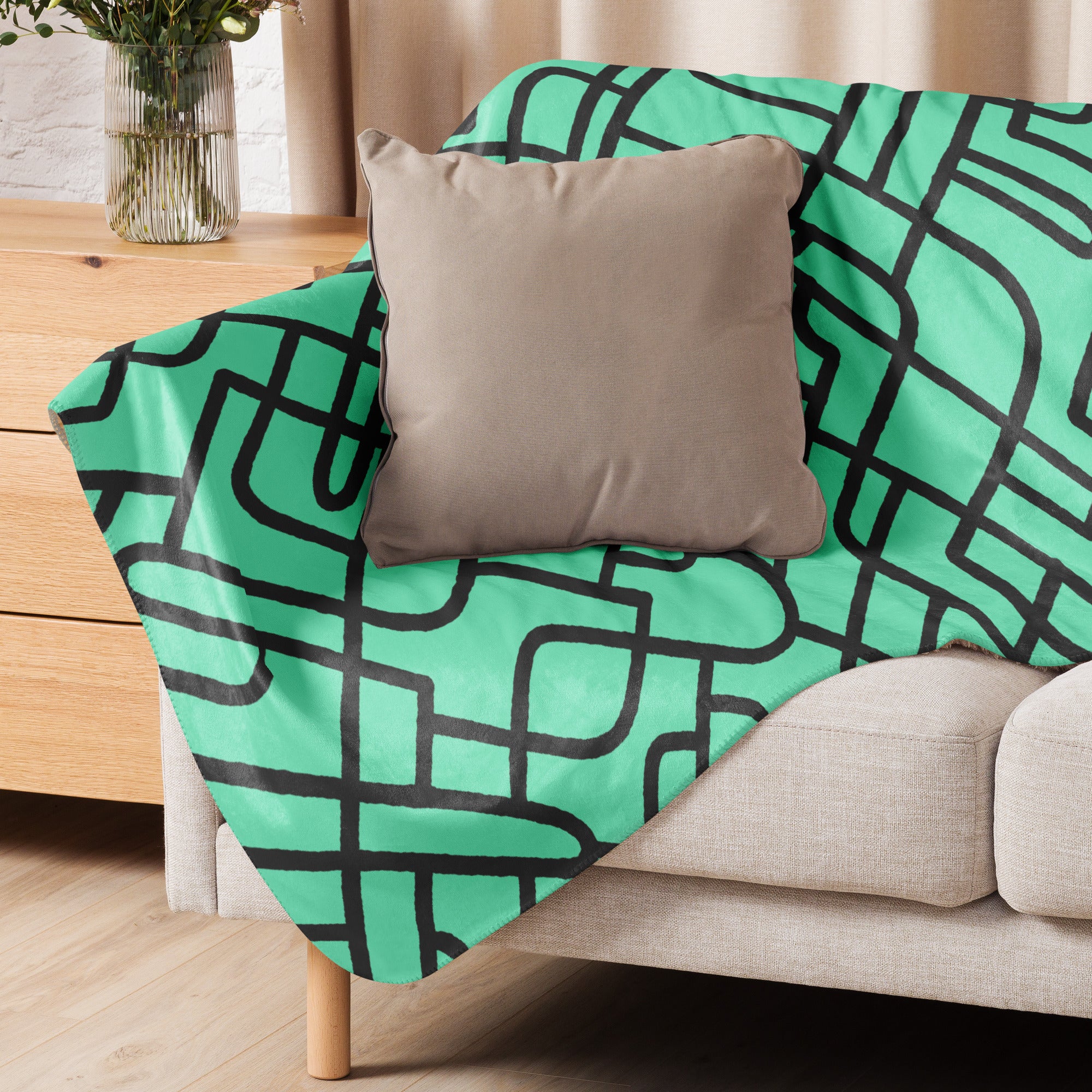 A cozy sherpa blanket with a modern geometric design draped over a sofa in a stylish living room setup.