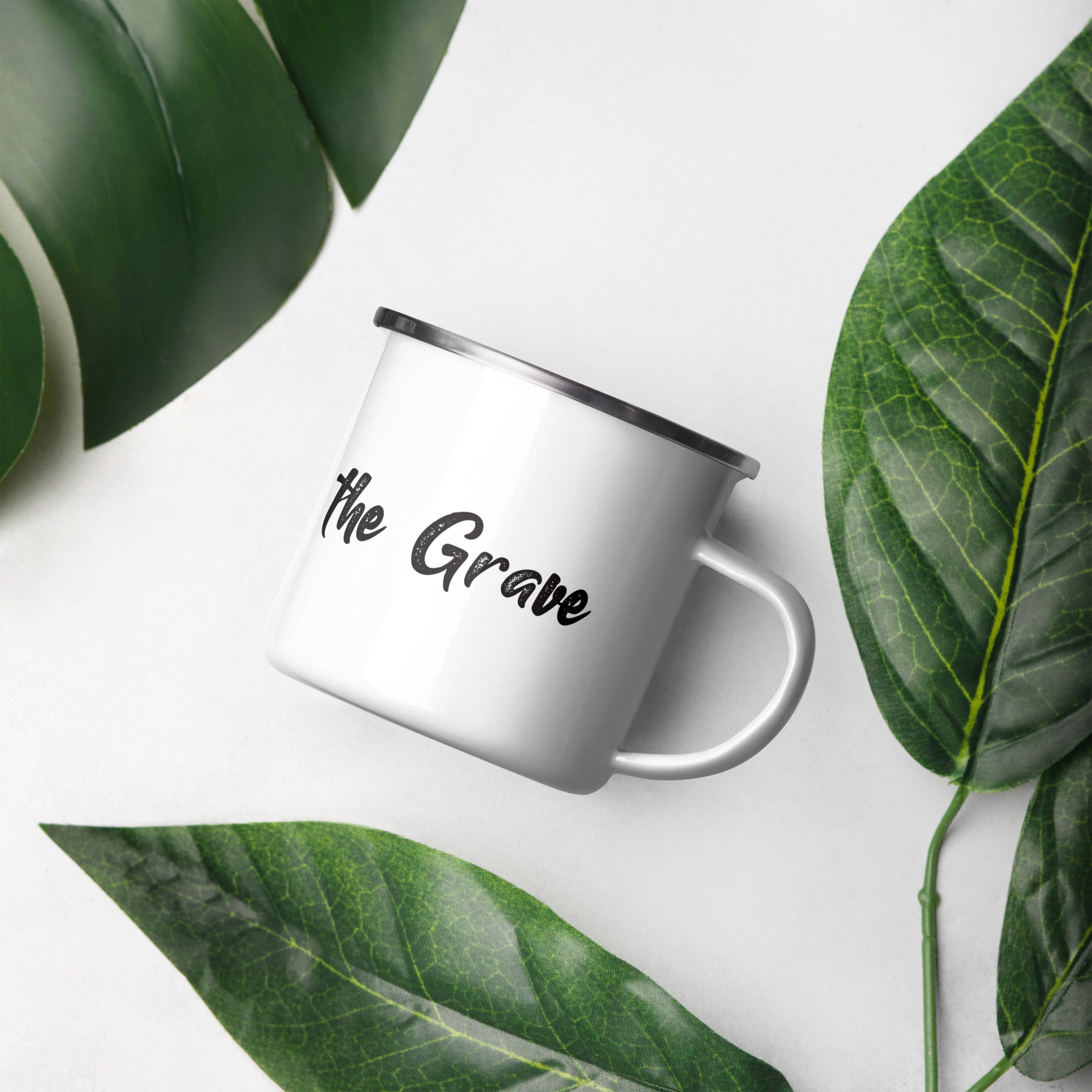 Close-up of the "Dapper to the Grave" enamel mug styled with green leaves for a fresh, modern look.