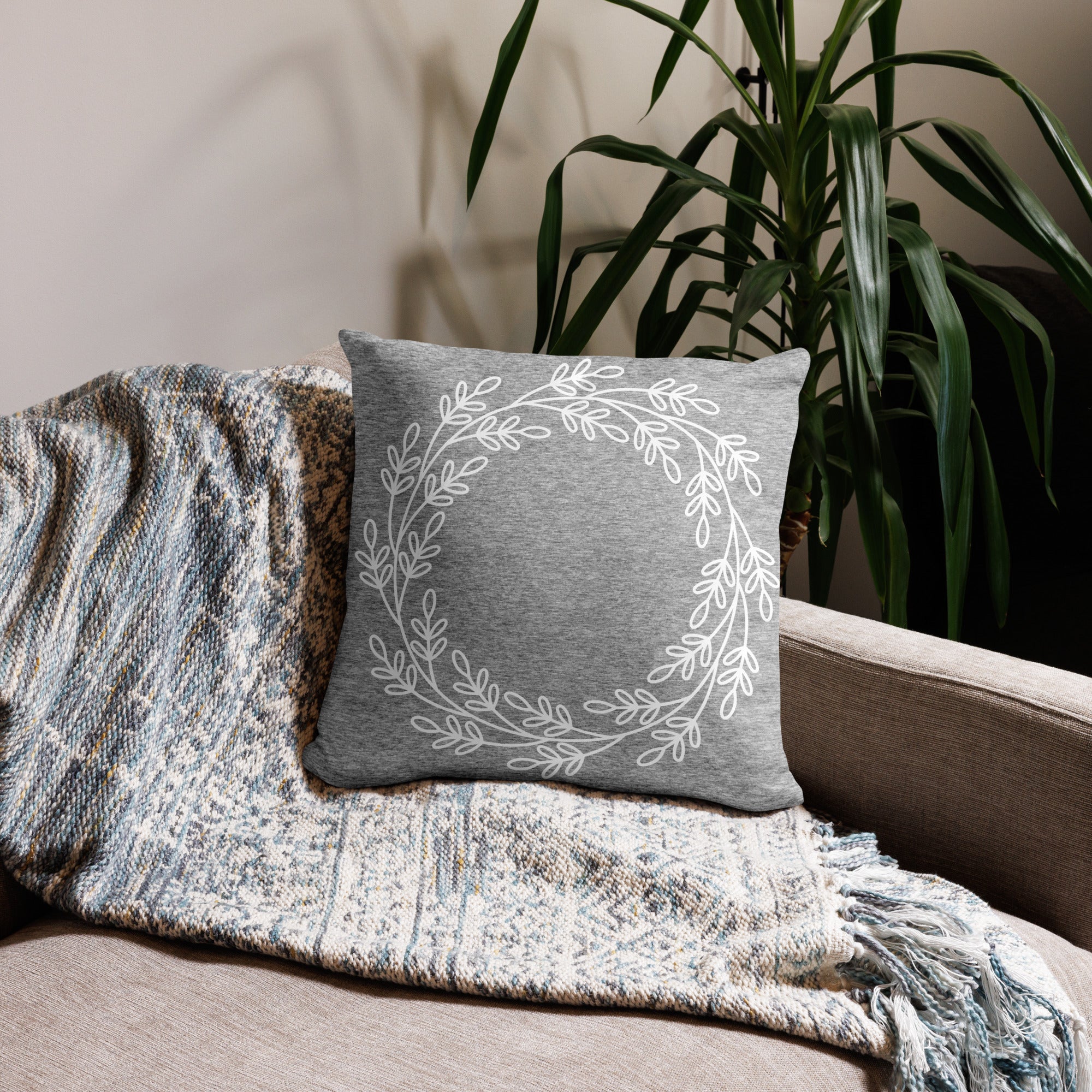 Gray pillow with a simple white leaf accent design, styled on a cozy sofa.