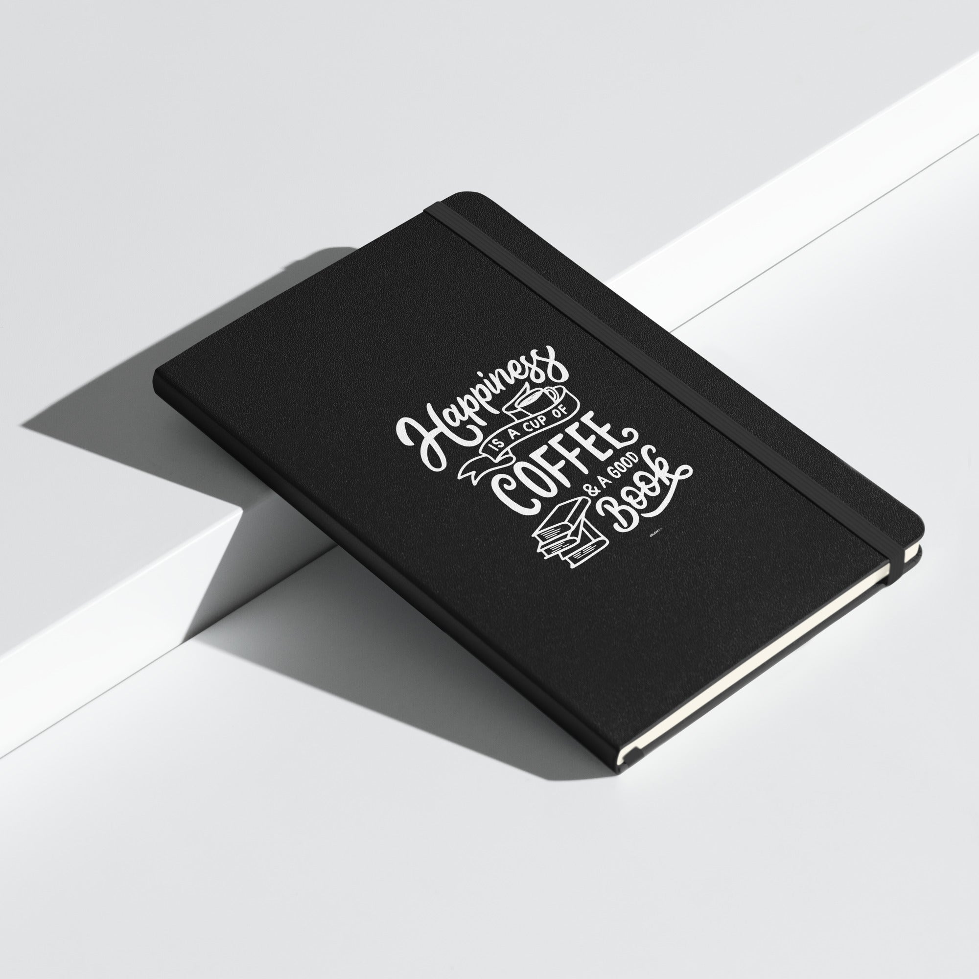 Angled view of the black "Happiness is a Cup of Coffee & a Good Book" hardcover journal on a white surface.