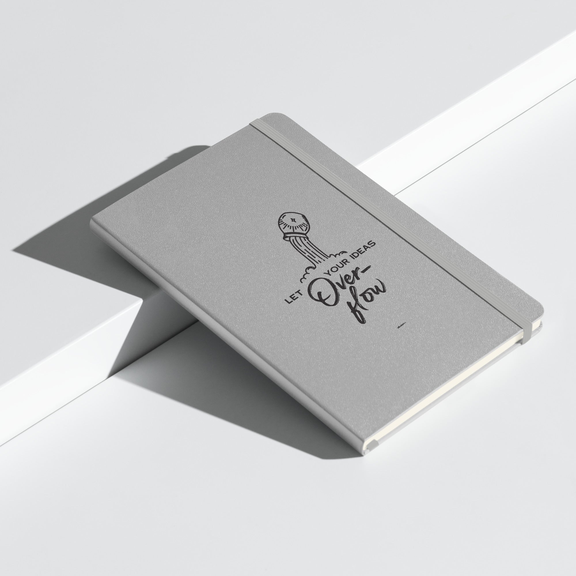 Hardcover silver journal with "Let Your Ideas Overflow" design, resting on a clean white surface.