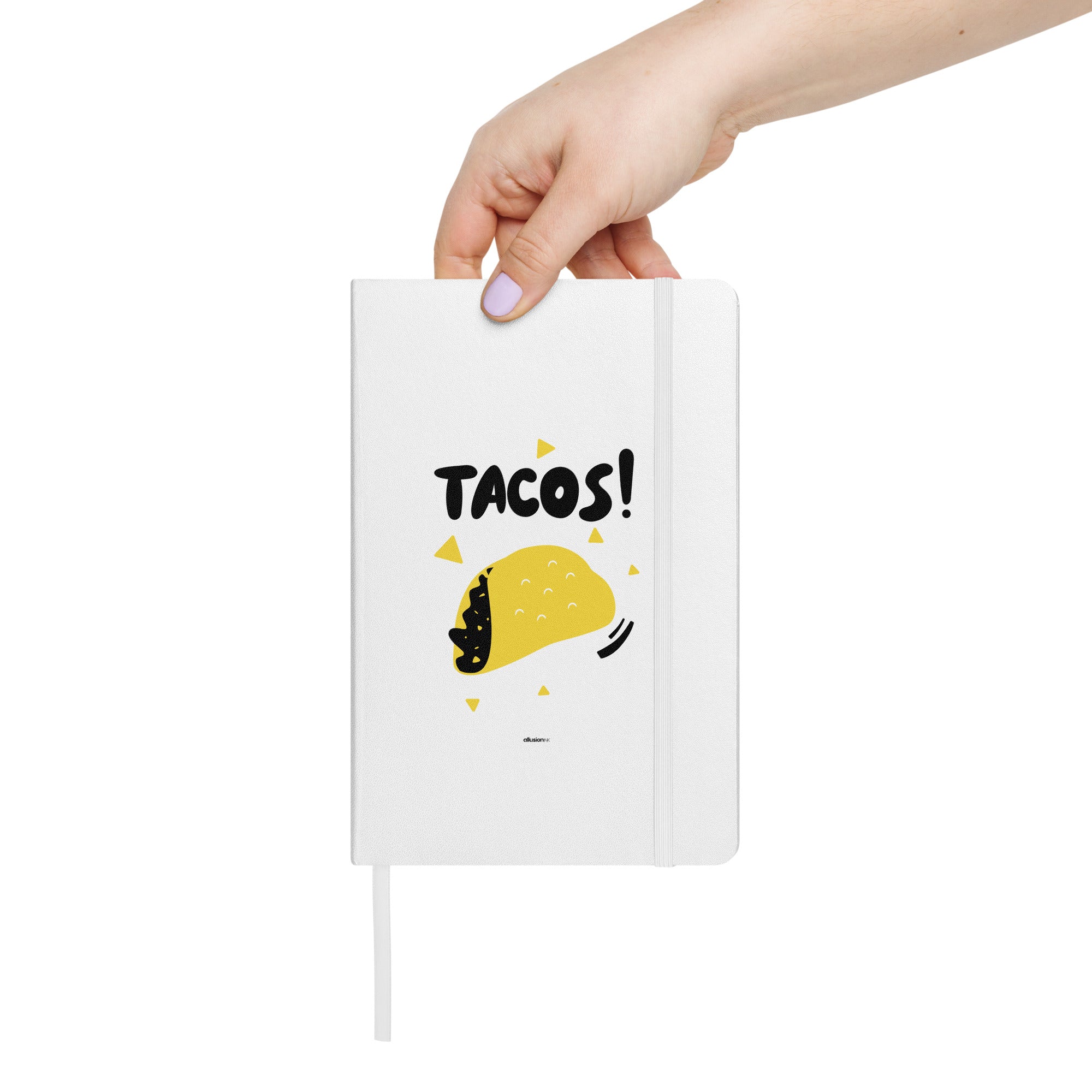 White hardcover UltraHyde notebook with bold "TACOS!" design and a yellow taco illustration, held in hand for size reference.