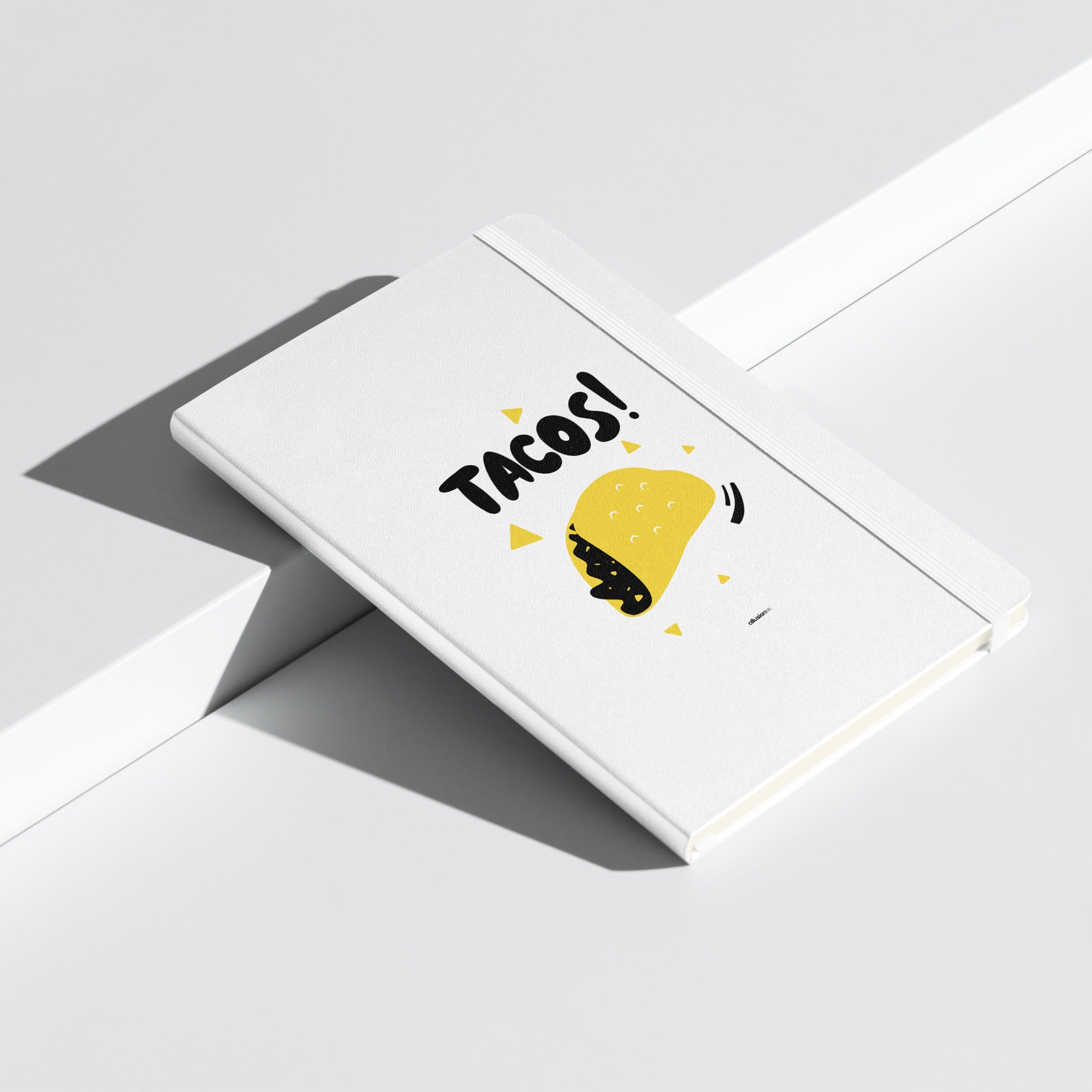 White UltraHyde hardcover notebook with bold "TACOS!" design, featuring a yellow taco illustration and matching elastic closure.