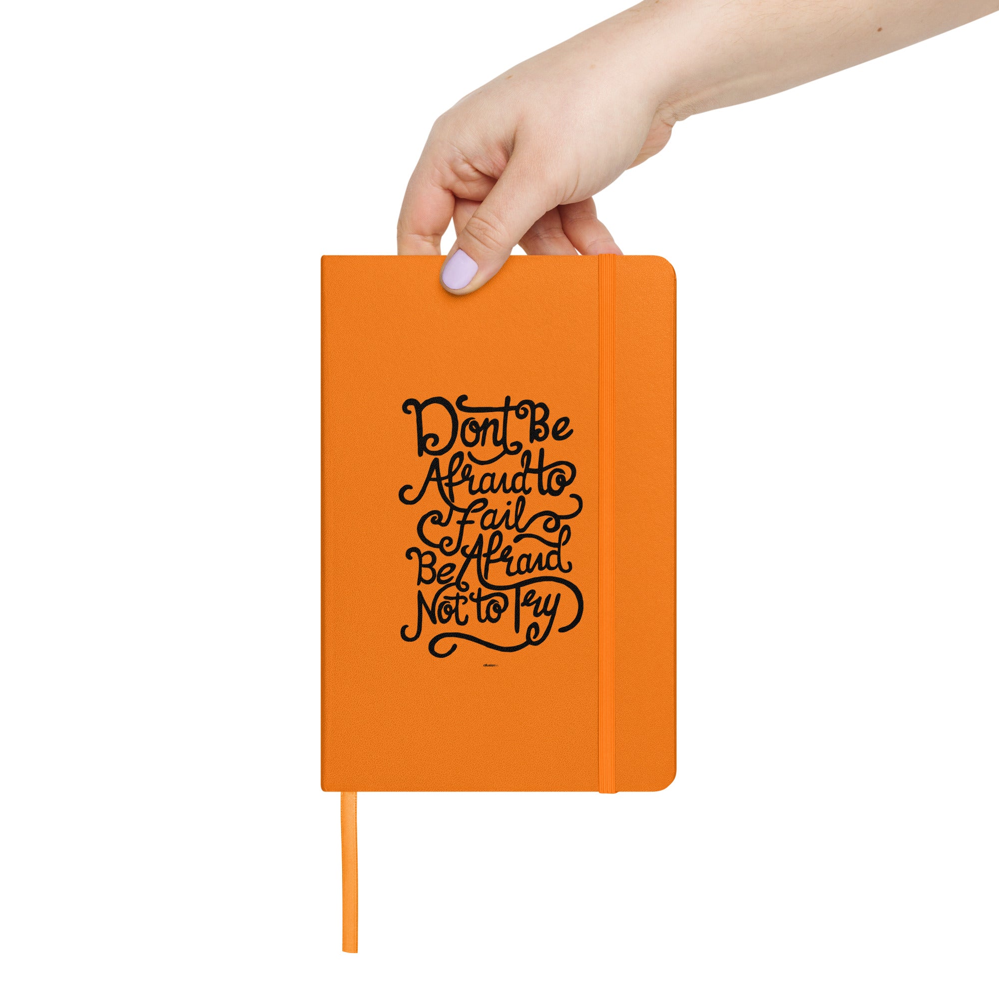 Hand holding an orange inspirational notebook with bold typography design.