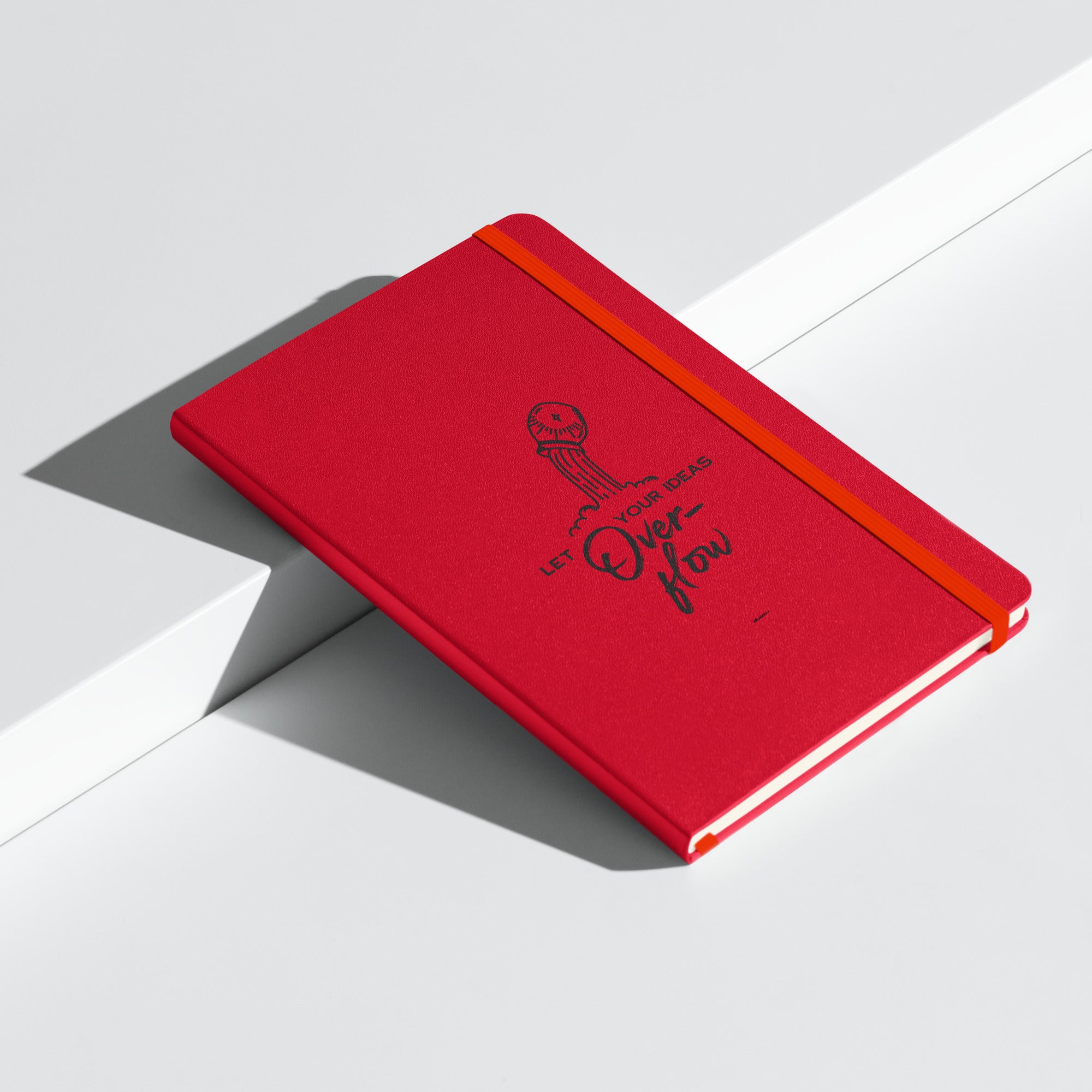 Hardcover red journal with "Let Your Ideas Overflow" design, placed on a minimalist white background.