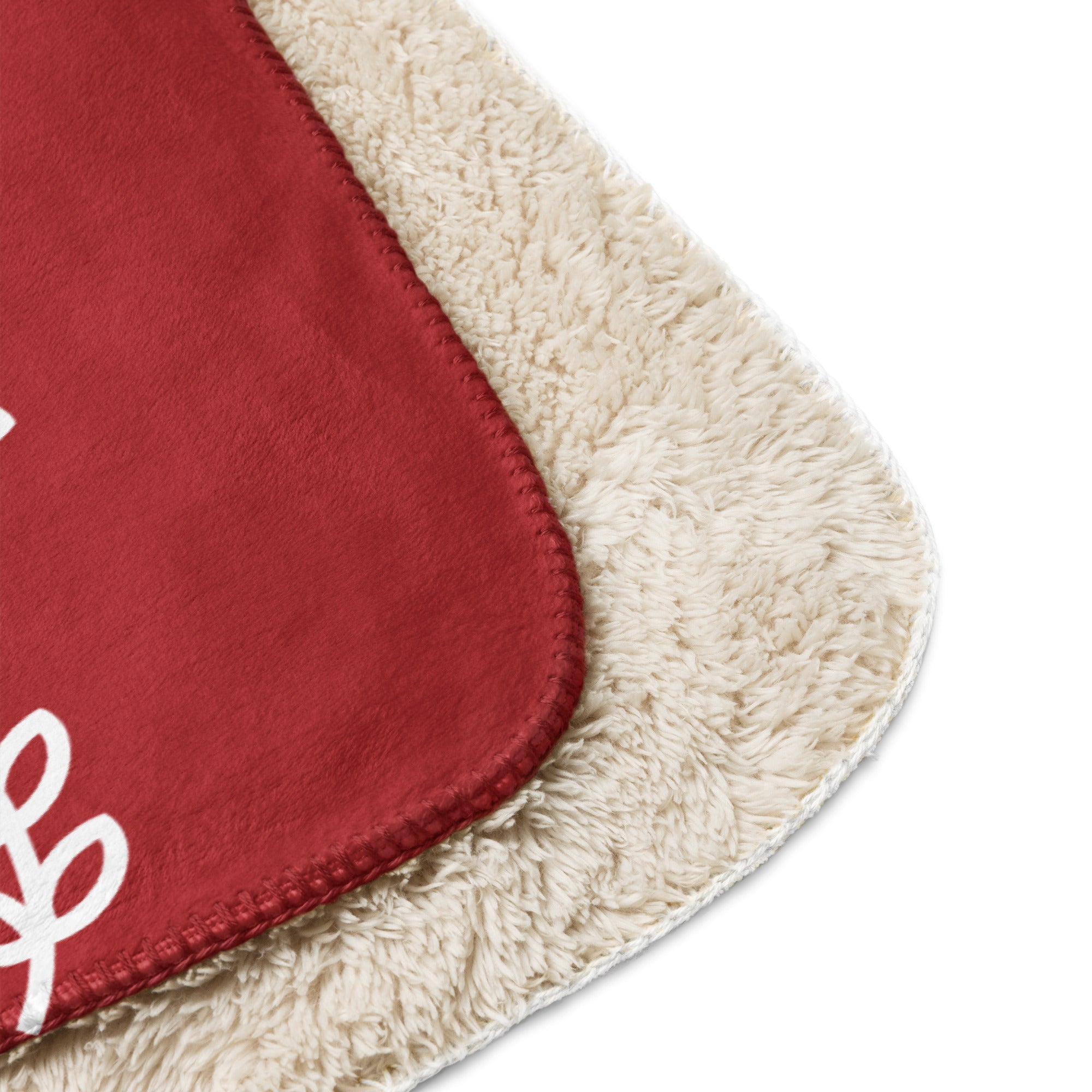 Detail view of red sherpa blanket edge with intricate white festive patterns.