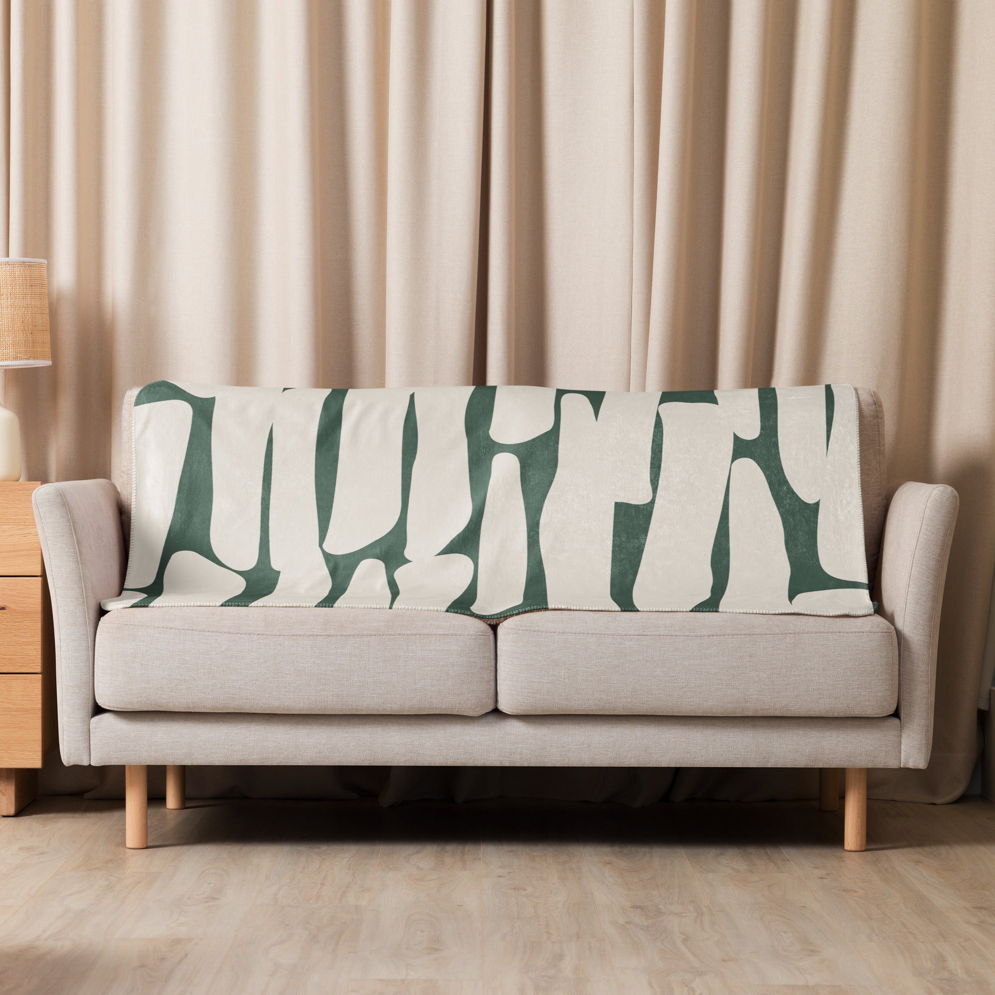 Sherpa blanket with green abstract botanical print draped over a sofa for cozy decor.