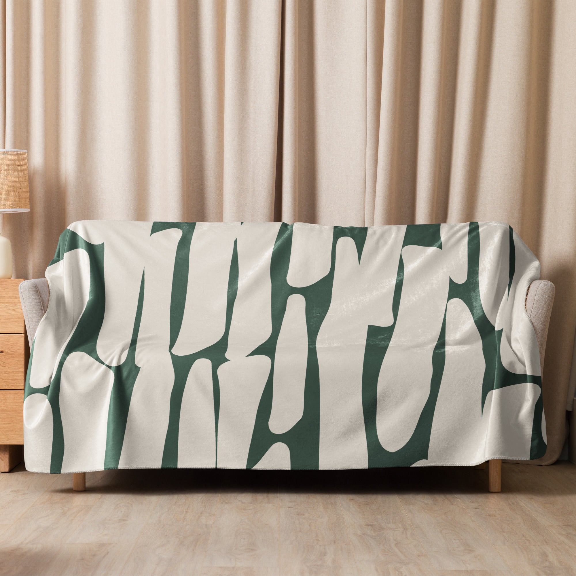 Sherpa blanket with green botanical design displayed fully on a light-colored sofa.