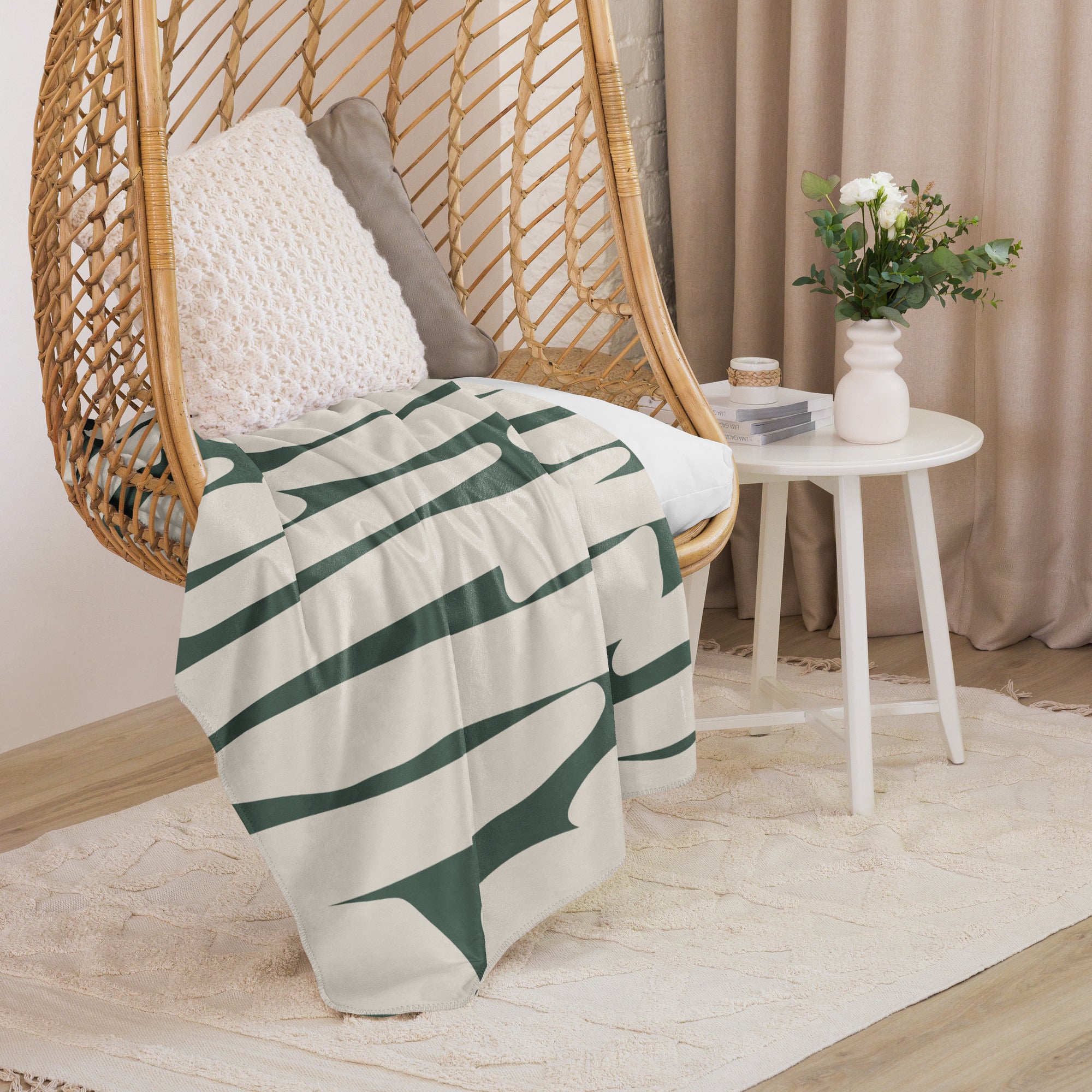 Sherpa blanket featuring a green abstract design displayed in a hanging chair with neutral accents.