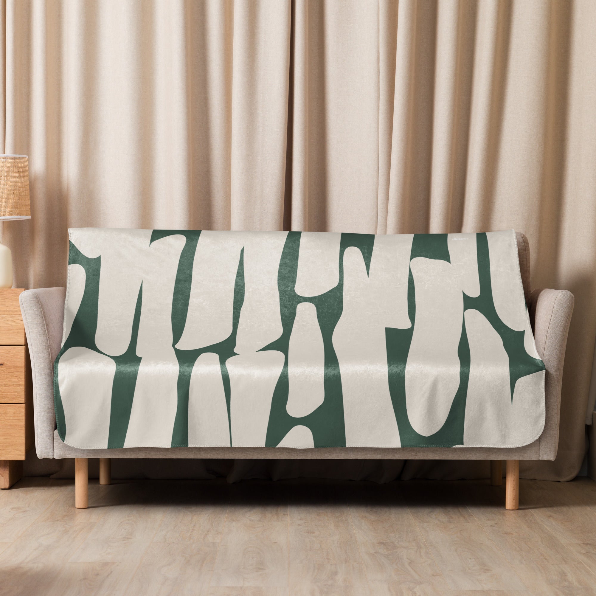 Green abstract sherpa blanket laid across a neutral-toned sofa for minimalist decor.