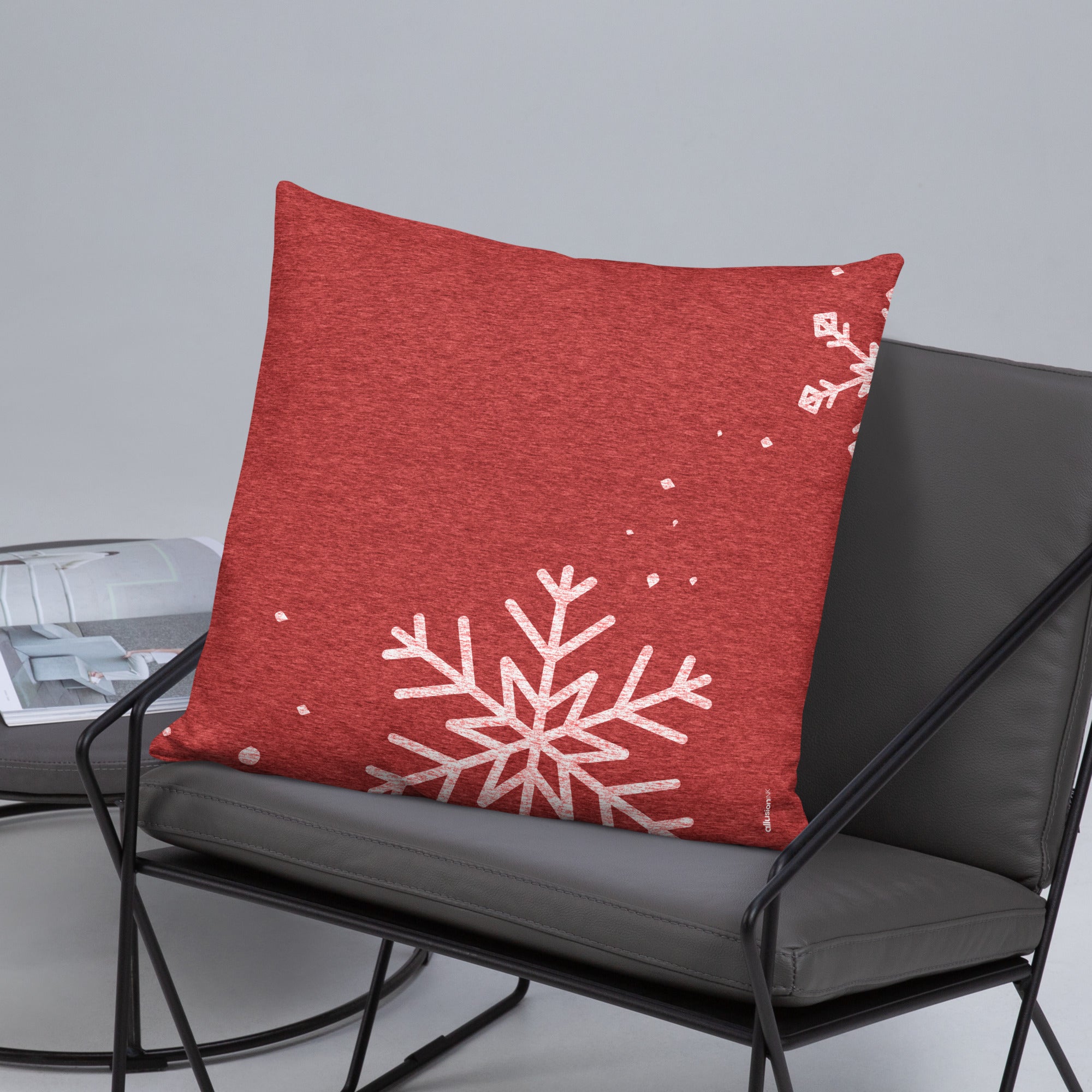 Back view of a red 22x22 snowflake pillow resting on a chair in a holiday-themed setup.