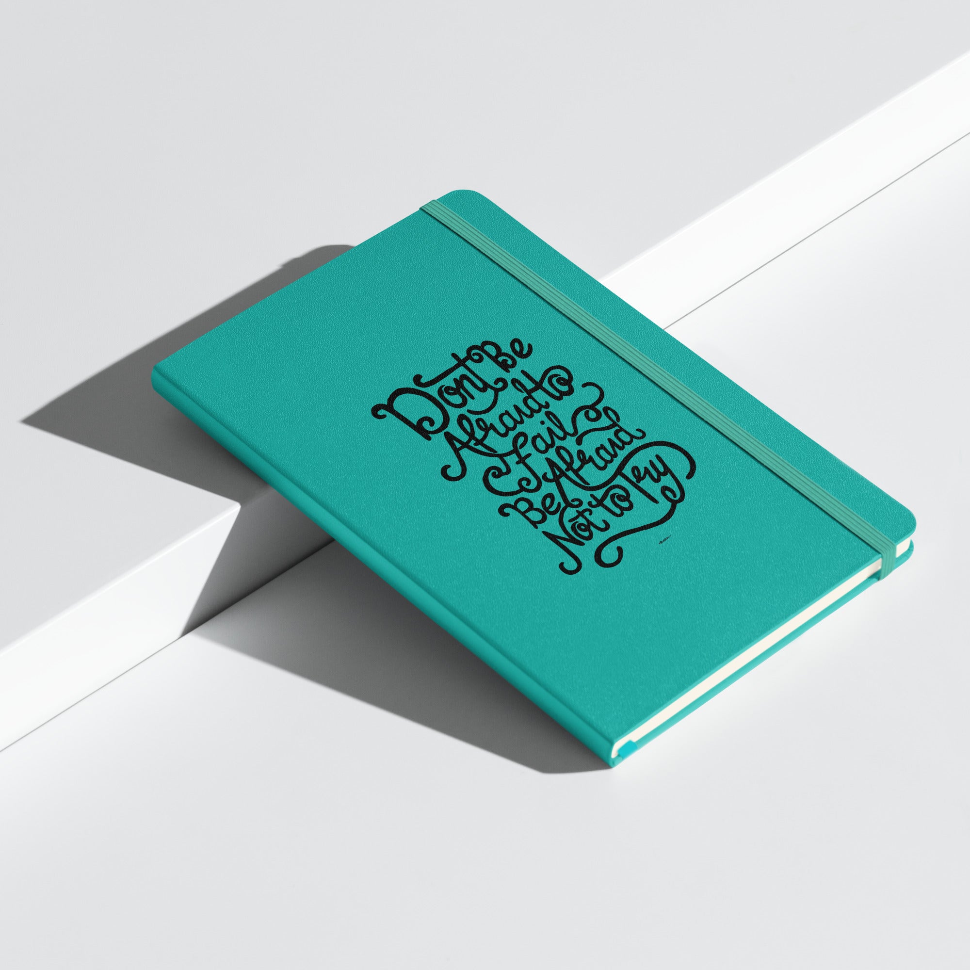 Turquoise inspirational notebook with bold lettering of the quote 'Don't be afraid to fail, be afraid not to try' on the cover.