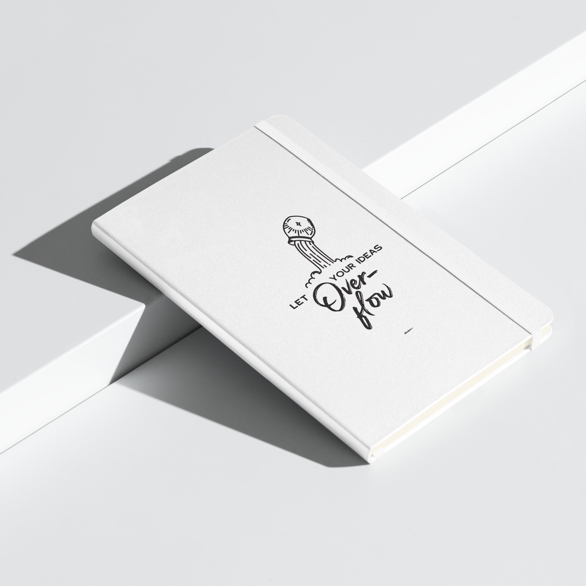 White hardcover notebook with 'Let Your Ideas Overflow' design, displayed at an angle.